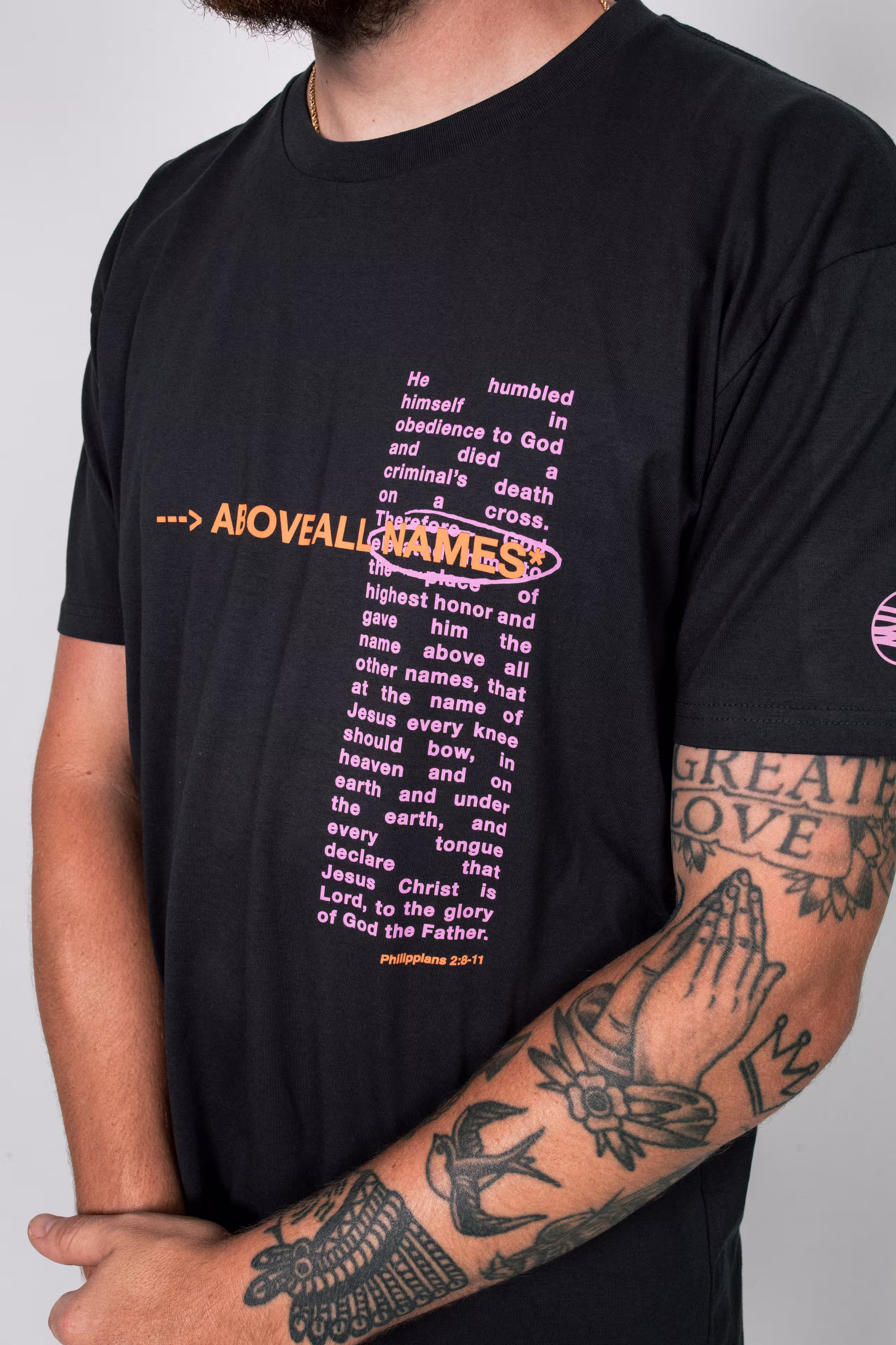man wearing a black t-shirt with a pink and orange print on the top right