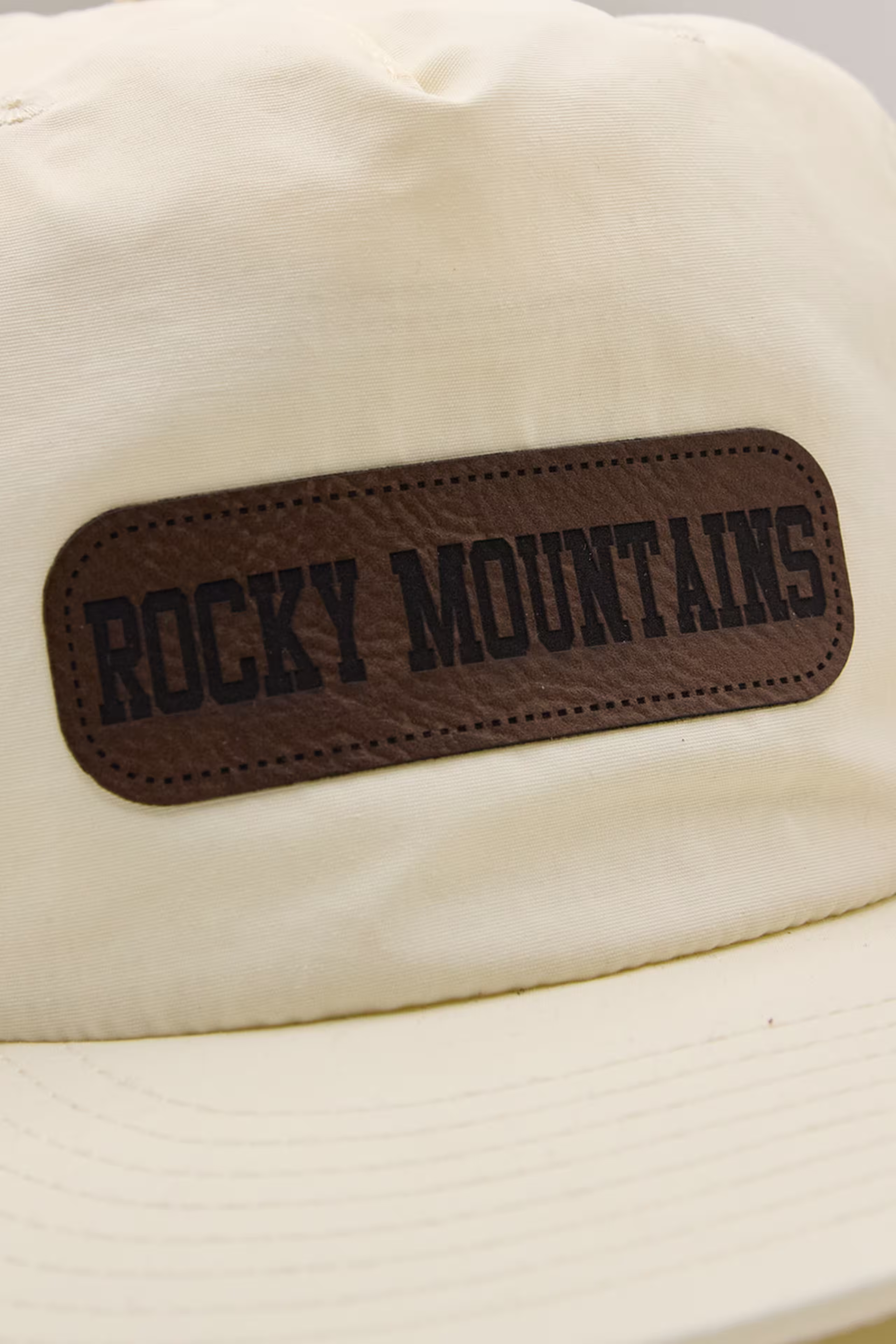 rounded corner rectangle faux leather patch on a cream-white hat